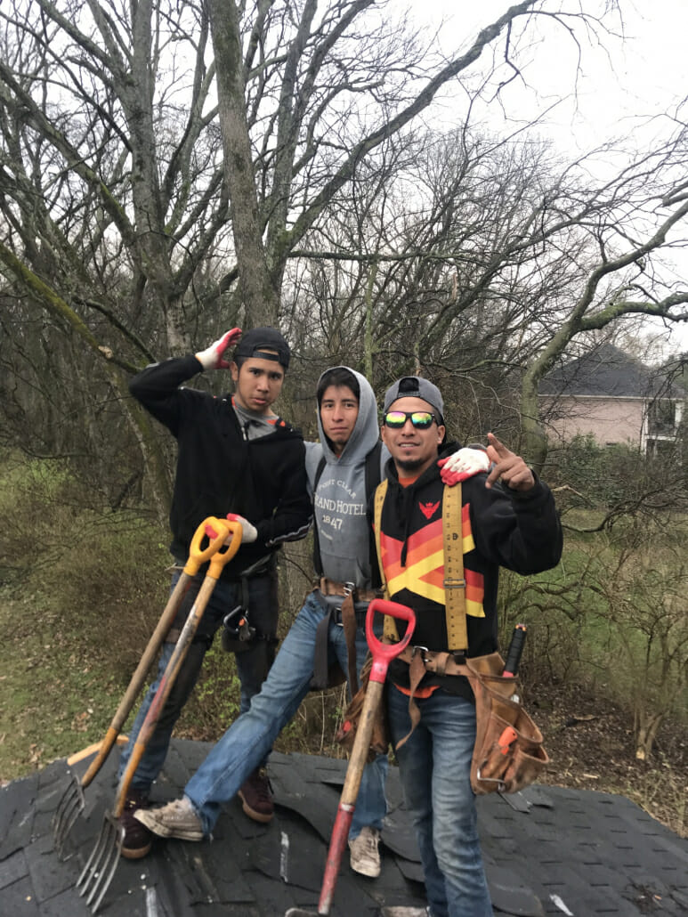 Three Thompson's Station roofers from Five Points Roofing Company smiling while working on a roof