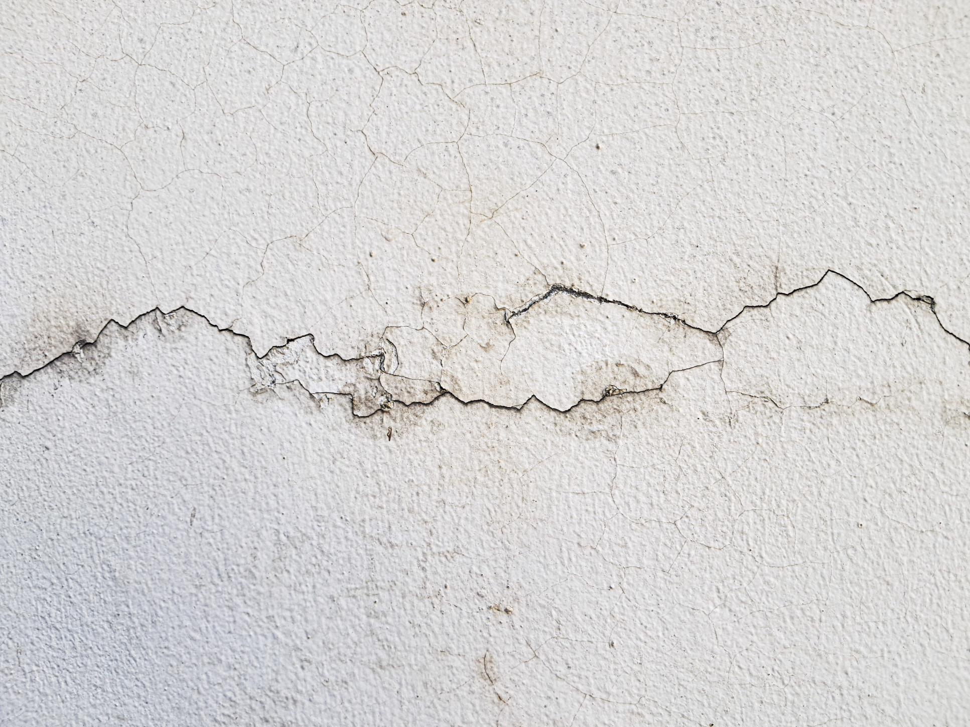 Cracks on a white interior wall caused by water damage or structural issues.