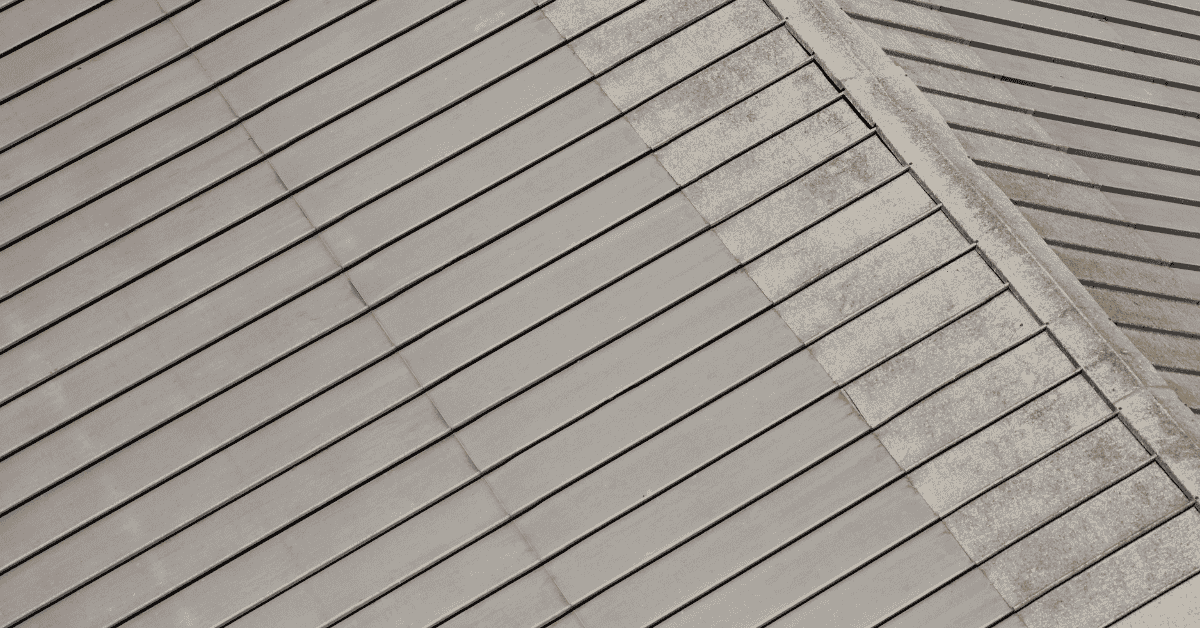 Close-up of a roof partially cleaned, showcasing the difference between moss-covered and clean roofing tiles.