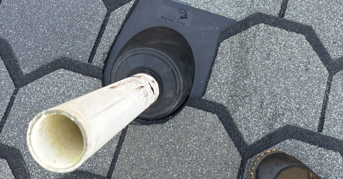 Pipe boot installed around a PVC pipe on a shingled roof, ensuring a watertight seal.
