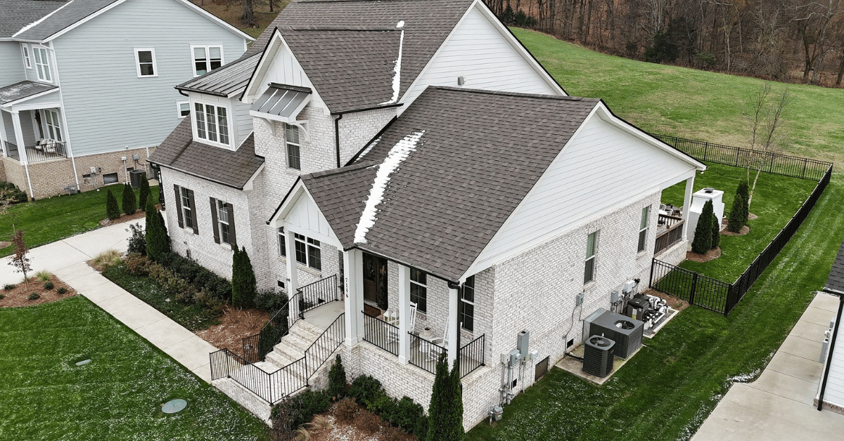 A modern two-story home with freshly installed asphalt shingle roofing, surrounded by green lawns and a neighborhood setting.