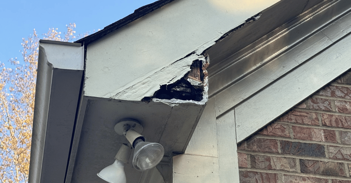 A damaged fascia board on a home’s edge, showing wood rot and wear caused by water damage.