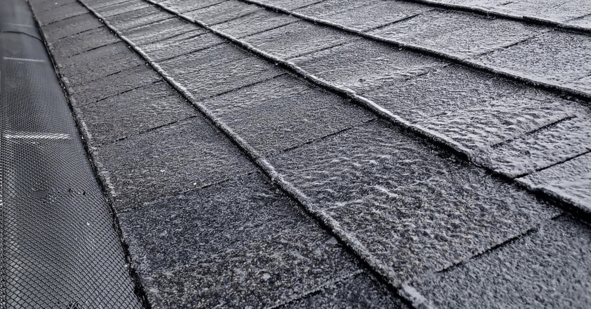 Frozen water covering asphalt shingles on a roof.