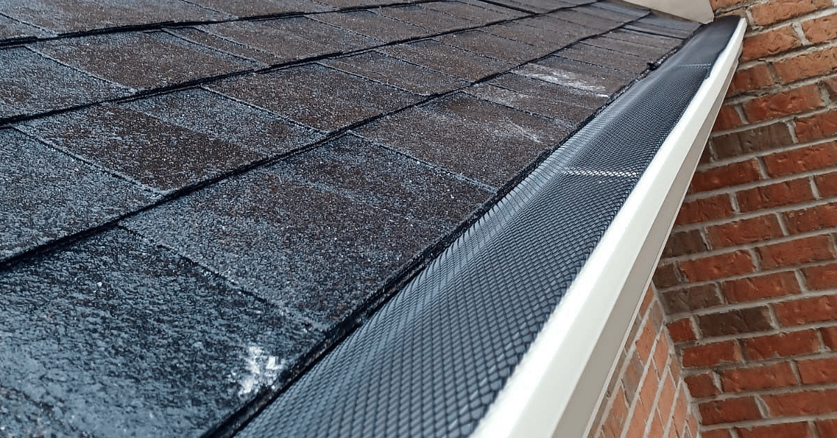 A clean gutter system with black mesh guards along a roof’s edge.