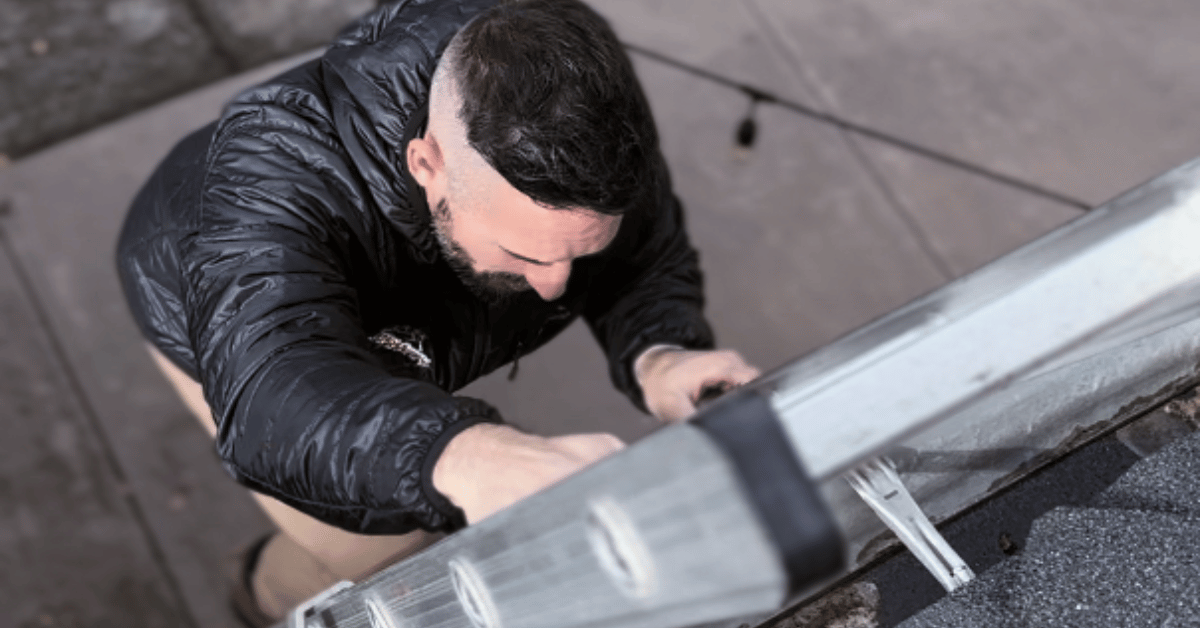 Close-up of a roofer carefully climbing a ladder during a roof inspection.