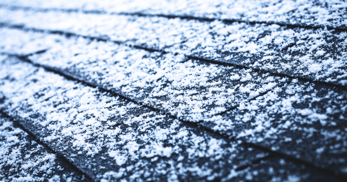 Close-up view of asphalt shingles lightly covered with snow.