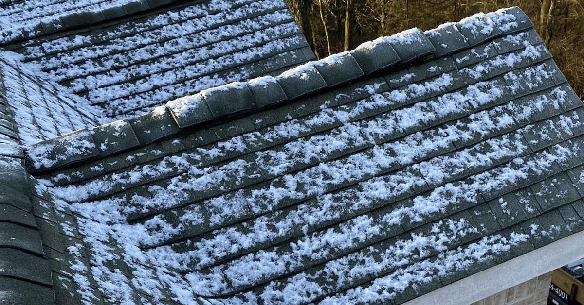 Roof shingles with patchy snow coverage under the winter sun.