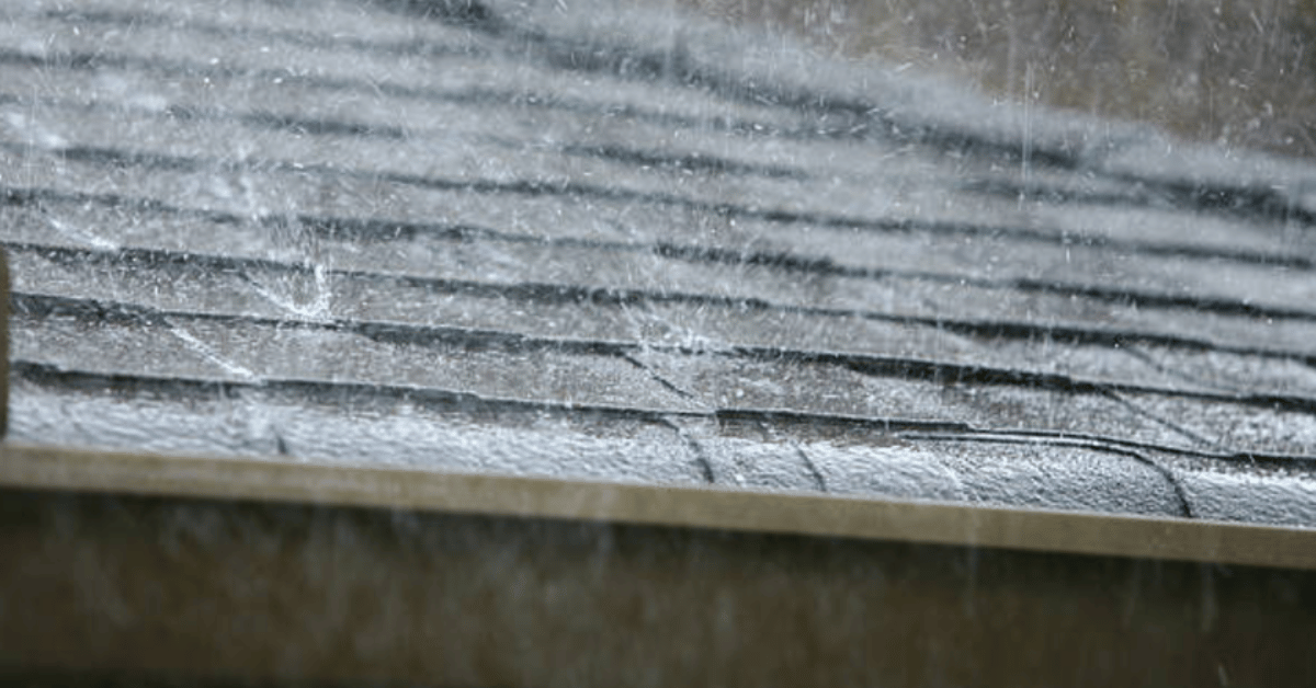 A close-up of wet shingles during a downpour, emphasizing the importance of durable roofing materials.