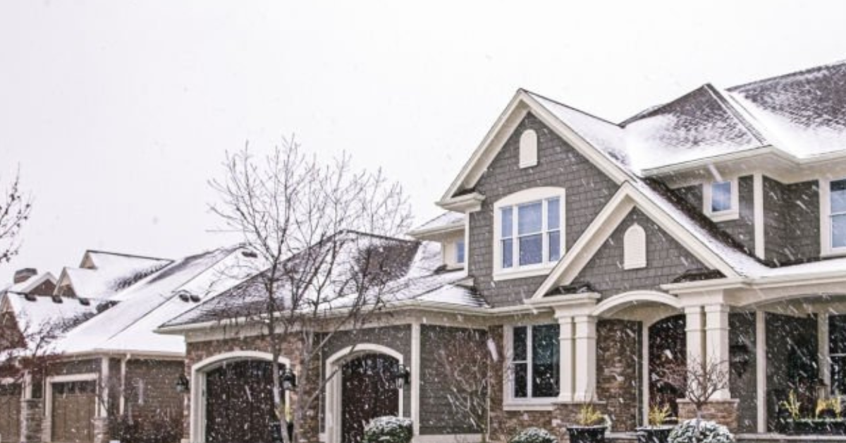 A home with a snow-covered roof during a light snowfall.