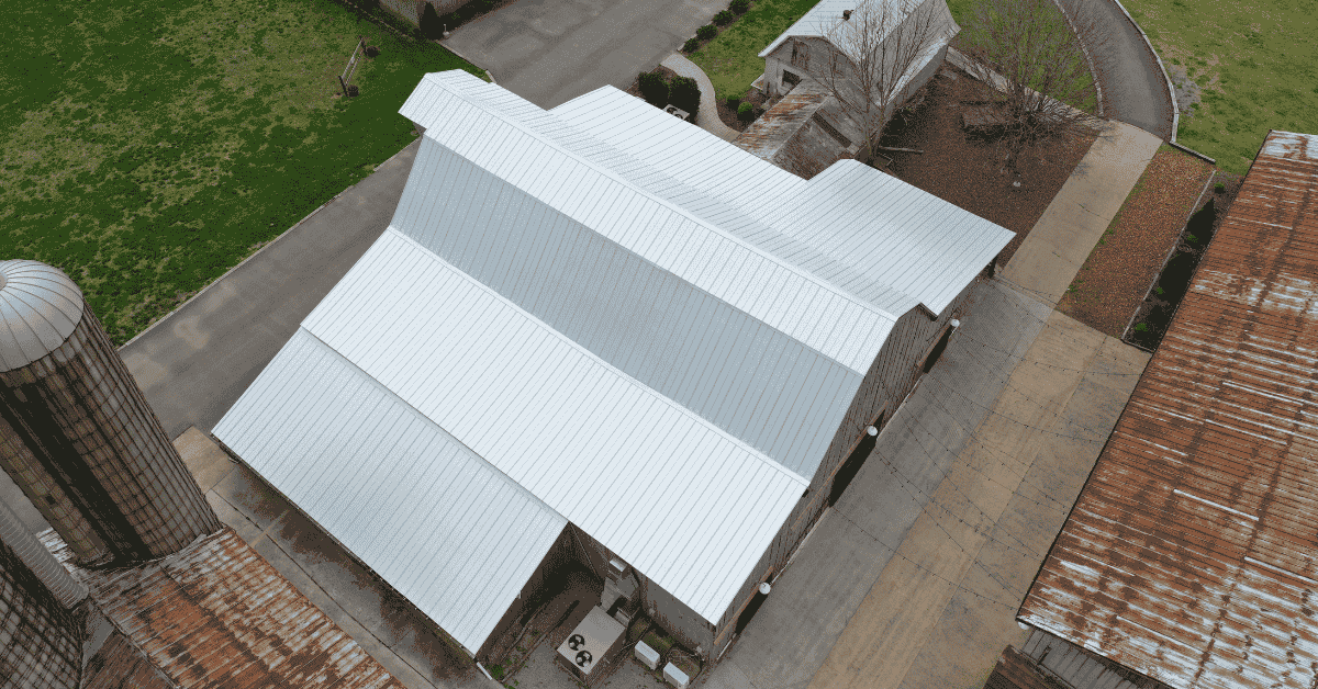 A gambrel roof on a white barn with steep lower slopes and shallow upper slopes.