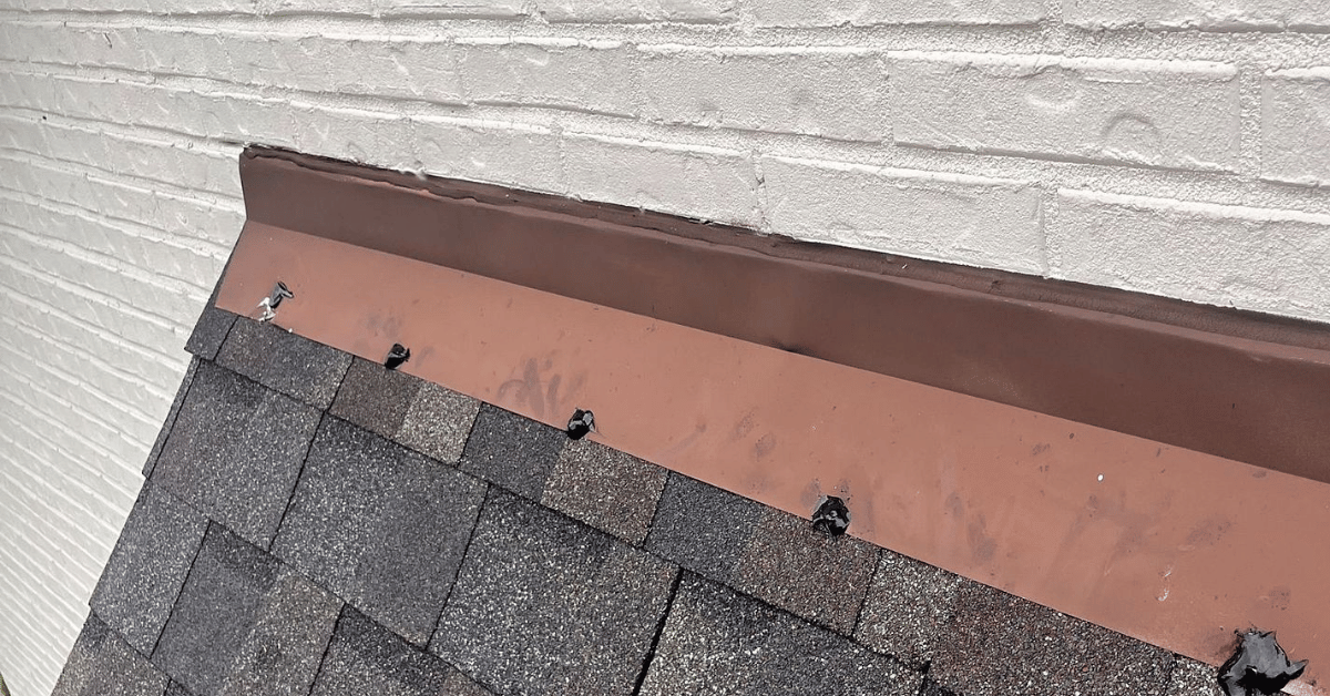 A close-up of metal roof flashing installed along a brick wall.