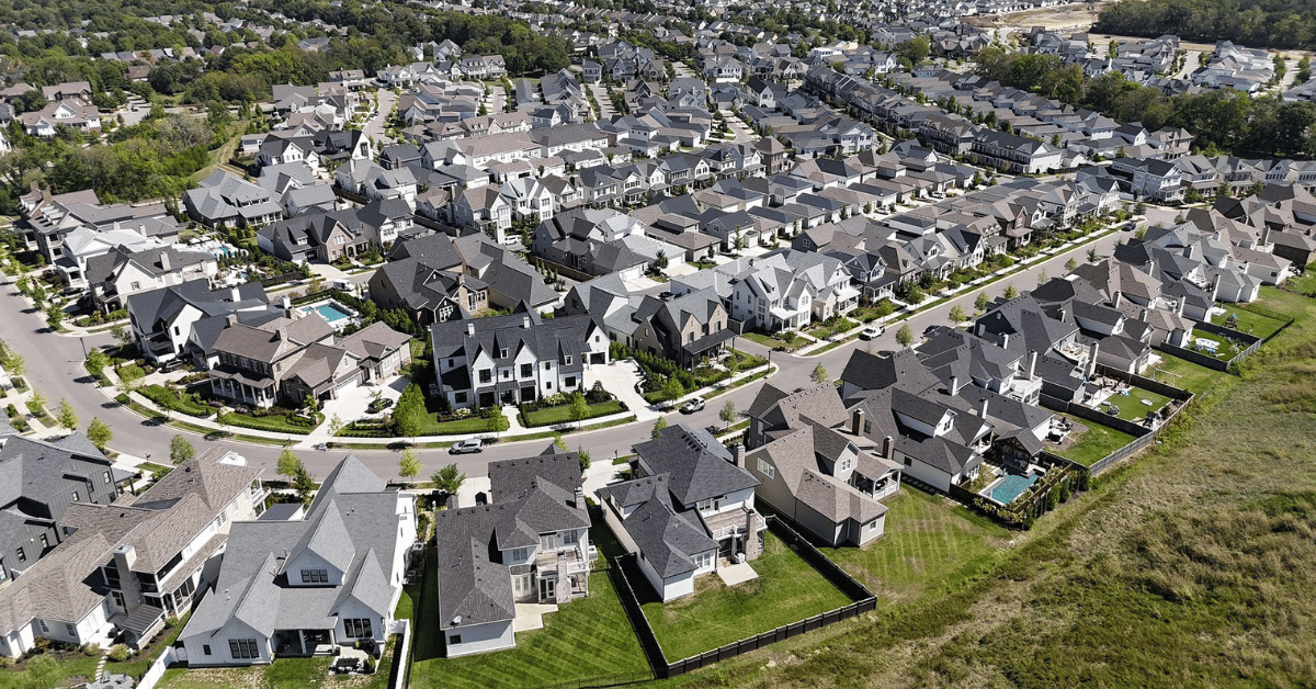 An aerial view of a residential neighborhood with various roof designs, including gable, hip, and flat roofs.
