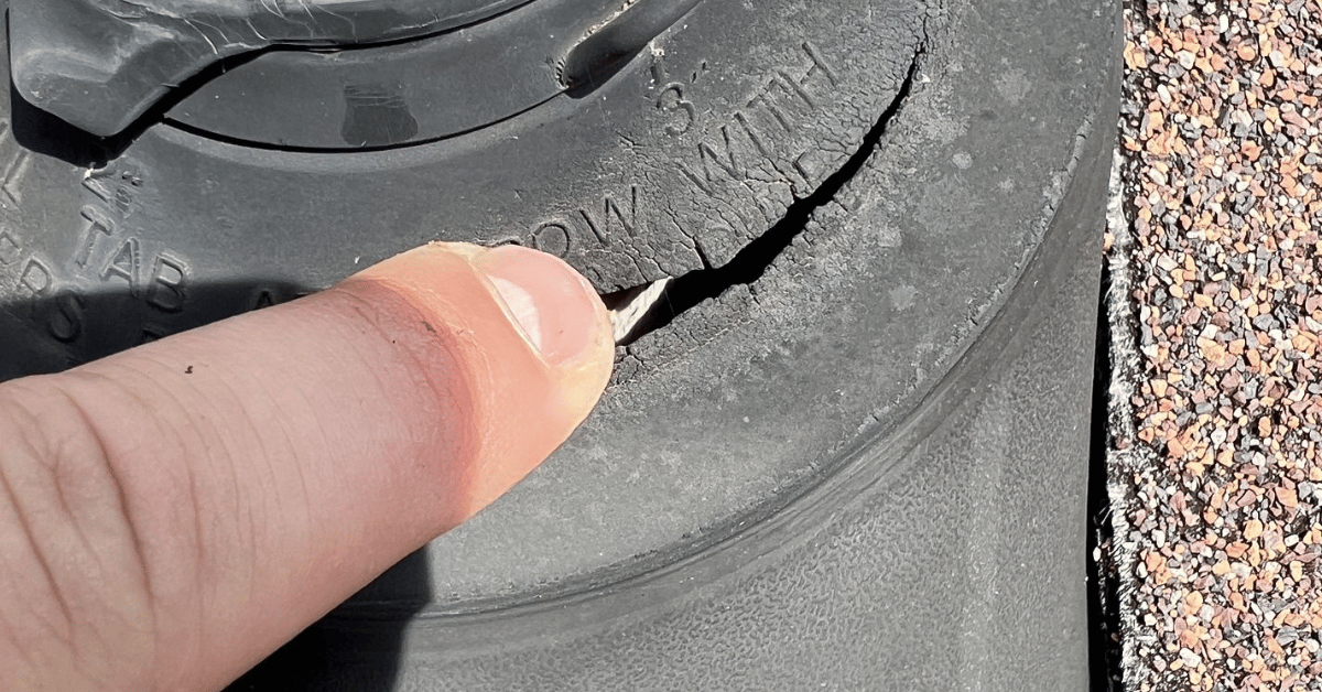 A roof vent pipe with an intact black rubber pipe boot surrounded by asphalt shingles.