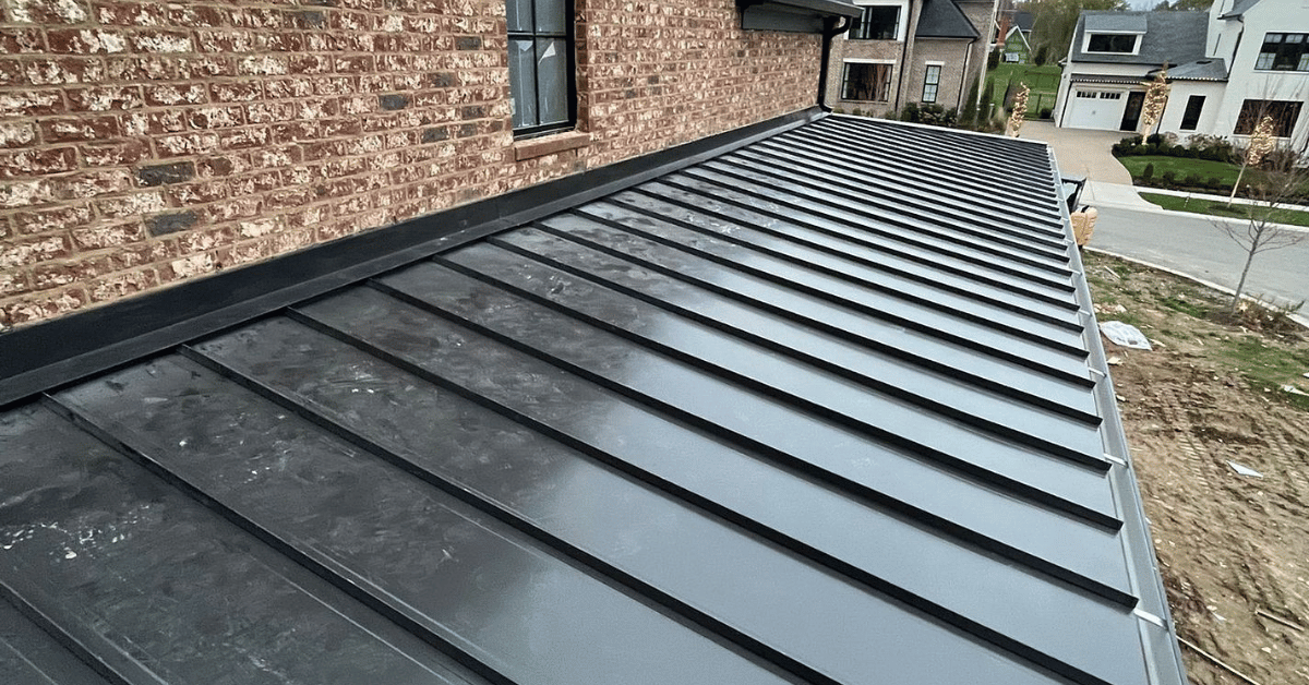A finished metal roof with a traditional design, surrounded by landscaped greenery.