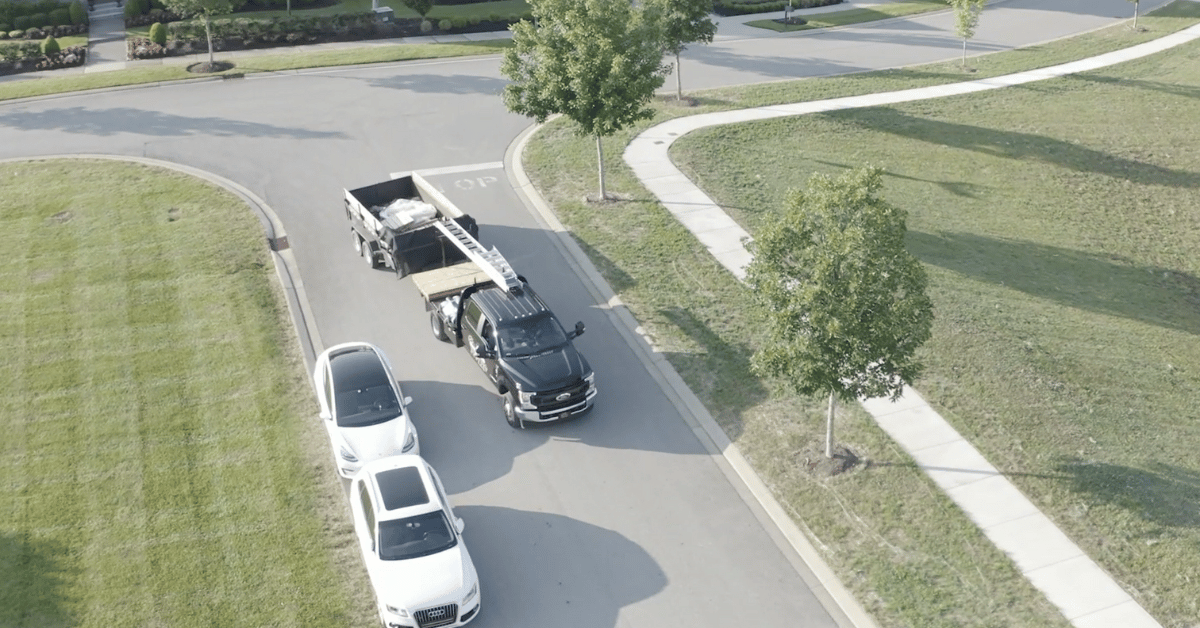 A roofing contractor's truck and trailer carrying roofing materials.