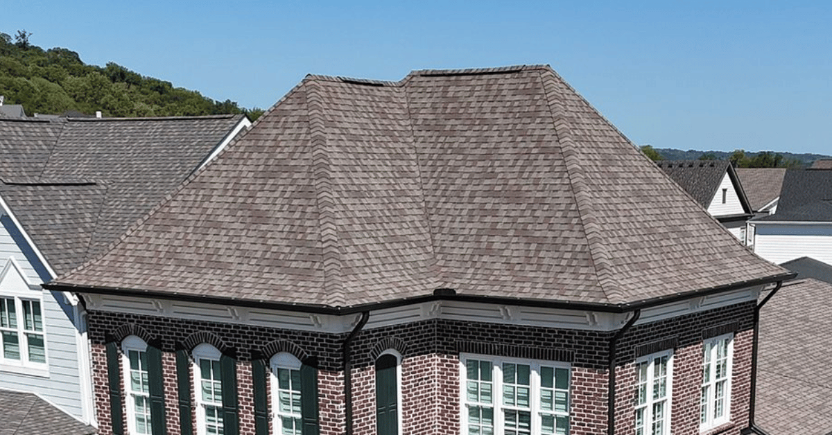 A hip roof on a brick house with symmetrical slopes meeting at the ridge.