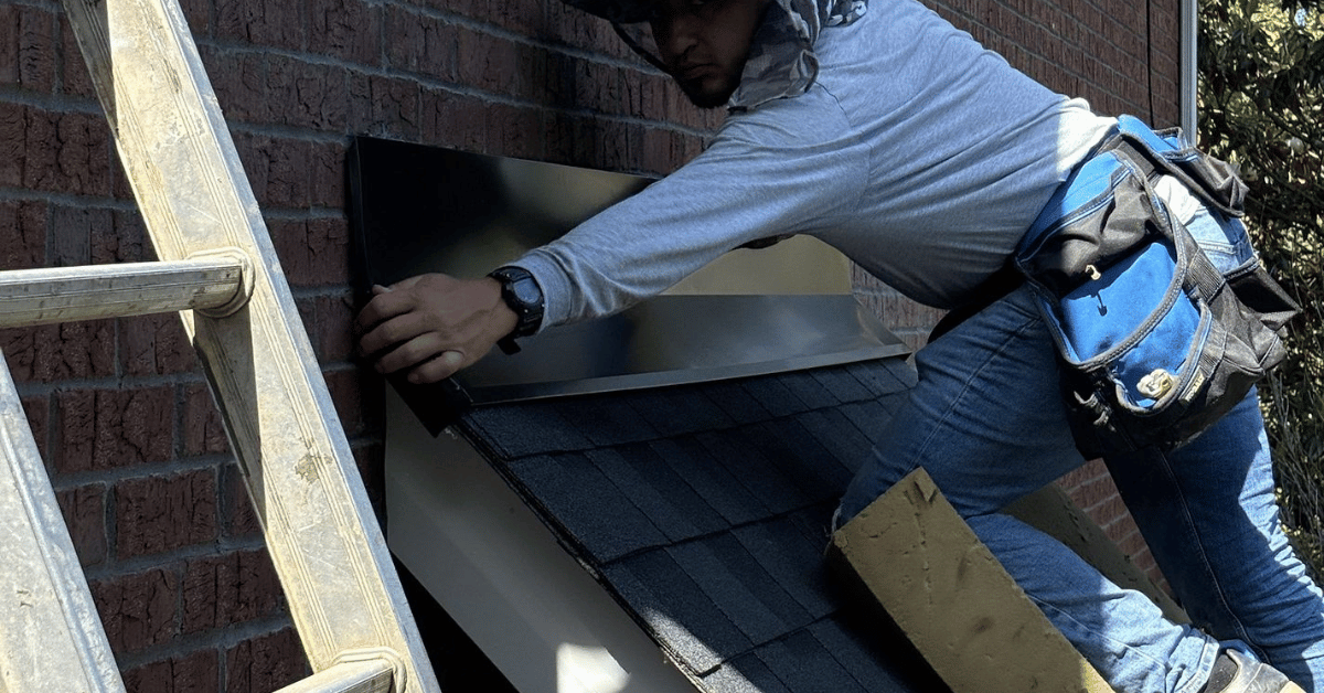 A roofing contractor securing metal flashing along a roof edge.