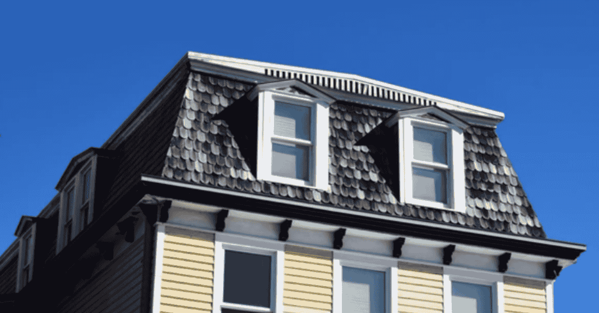 A yellow house with a mansard roof featuring dormer windows for additional living space.