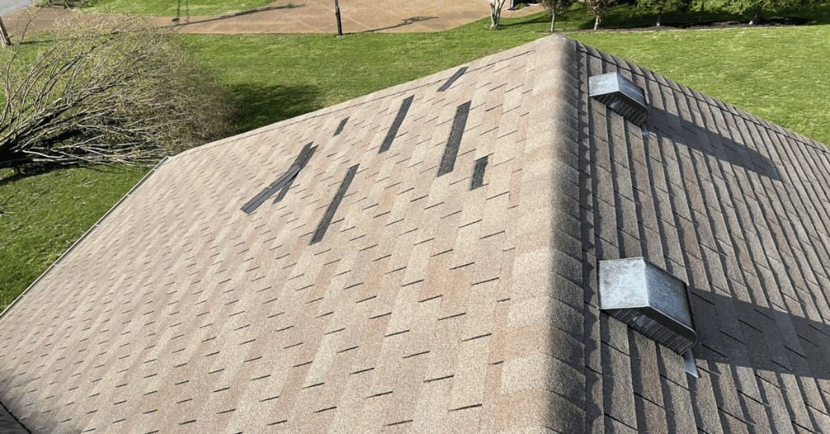 A roof with several missing shingles after a hailstorm