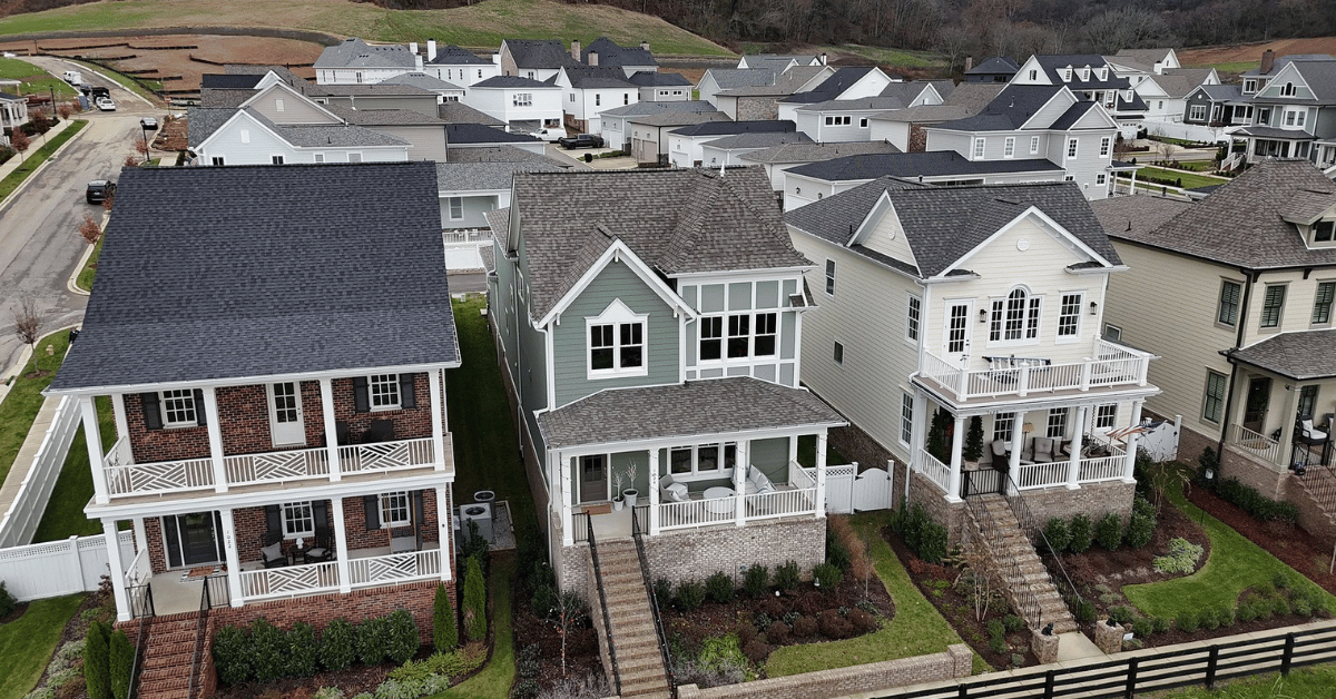 A neighborhood of homes with diverse roof designs, including gable, hip, and shed roofs, surrounded by greenery.