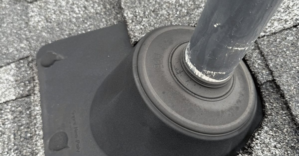 A roofing contractor applying sealant to the base of a pipe boot on a roof.