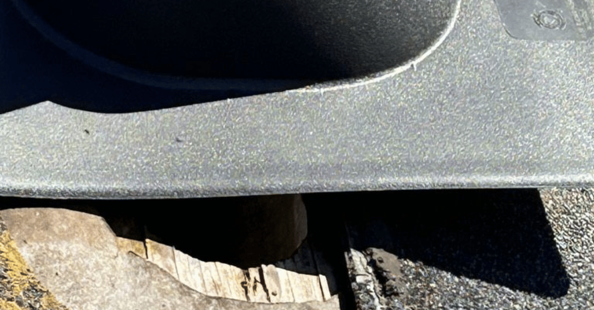 A roofing contractor applying sealant to the base of a pipe boot on a roof.