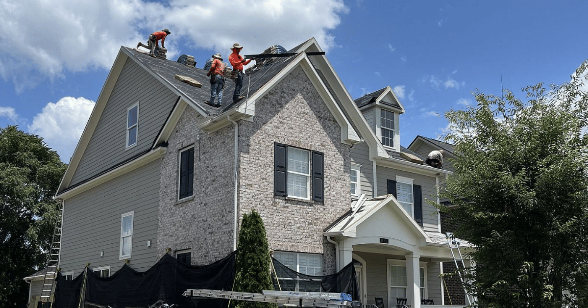 Roofing contractors performing a roof replacement with asphalt shingles.