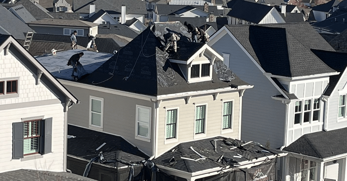 Roofers working on a home, installing underlayment and shingles as part of a comprehensive roofing project.