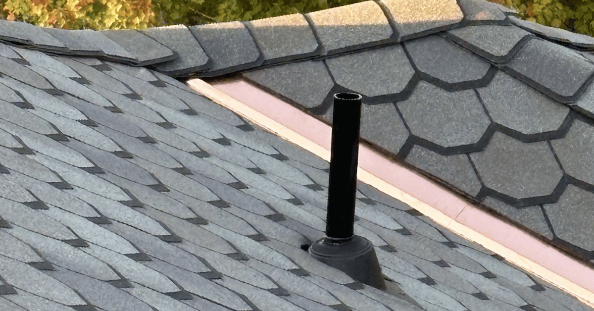 A roof vent pipe with an intact black rubber pipe boot surrounded by asphalt shingles.