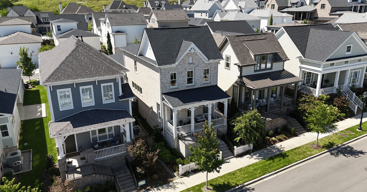 Three homes in a row with modern gable and hip roof designs in neutral tones.