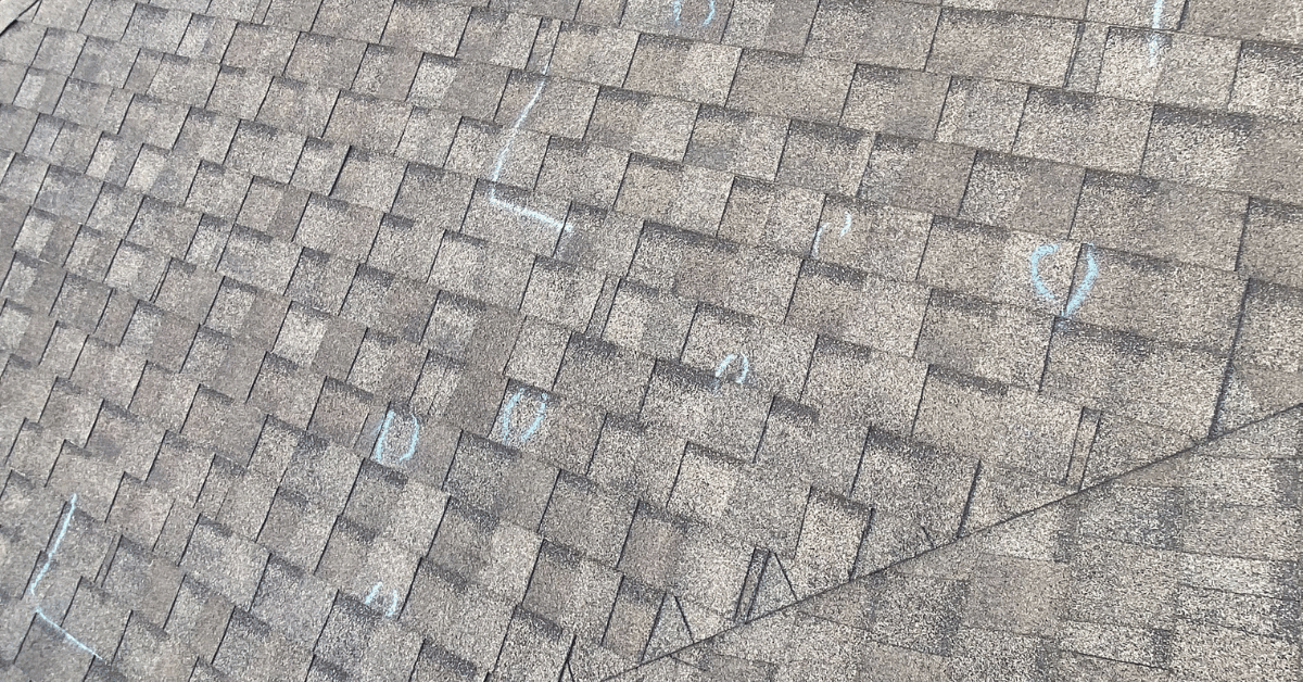 Roof with multiple inspection marks indicating Tamko shingle damage.