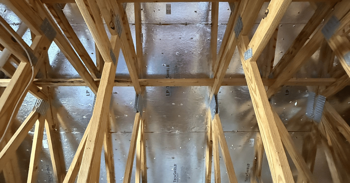 Exposed wooden attic framing with a reflective radiant barrier installed.