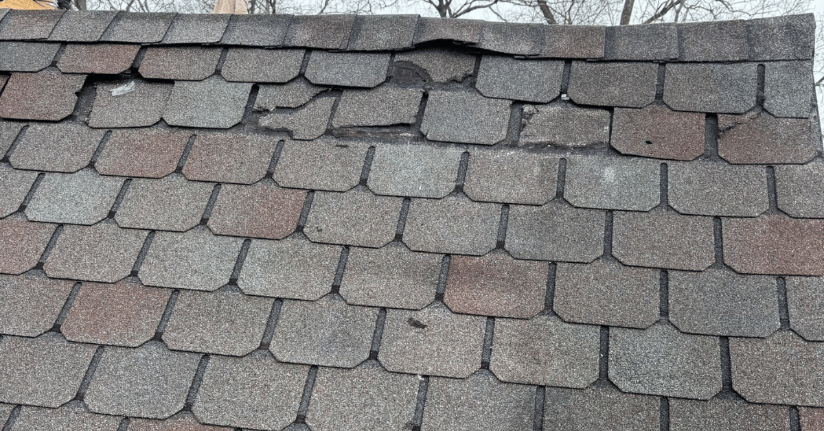 A damaged roof with cracked, missing, and curling shingles.