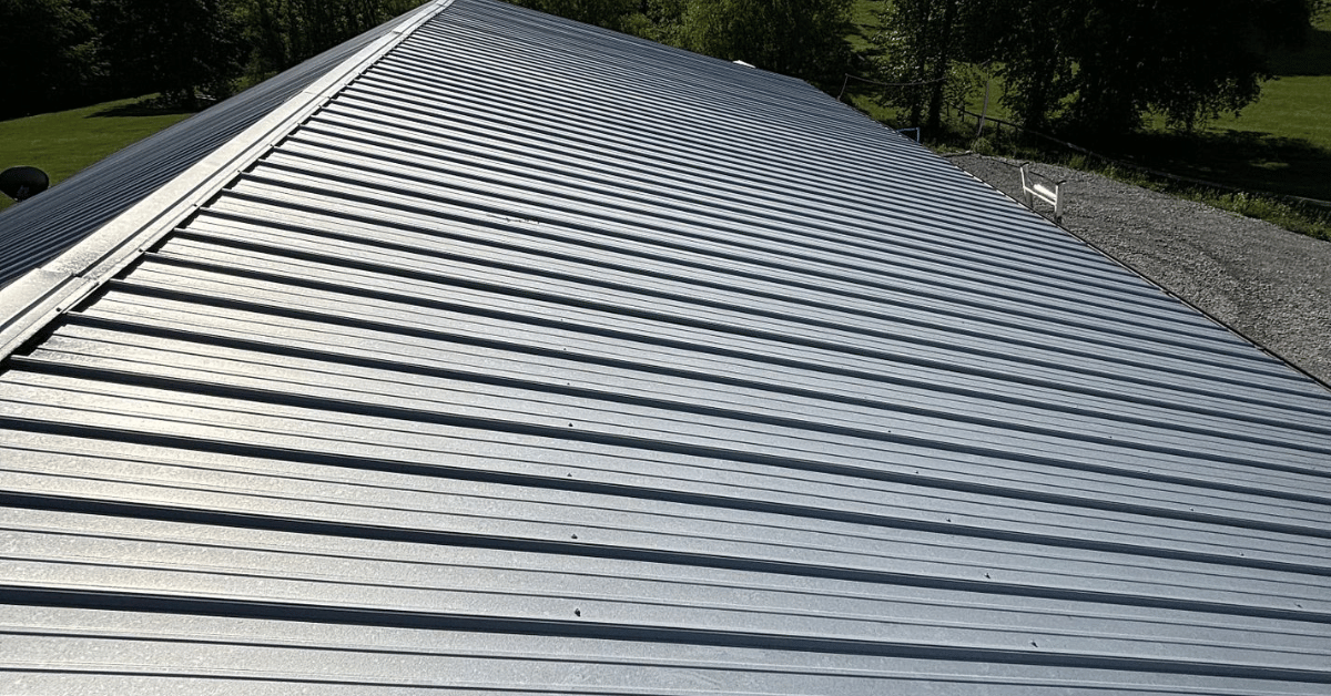 A close-up of a sleek, silver metal roof under bright sunlight.