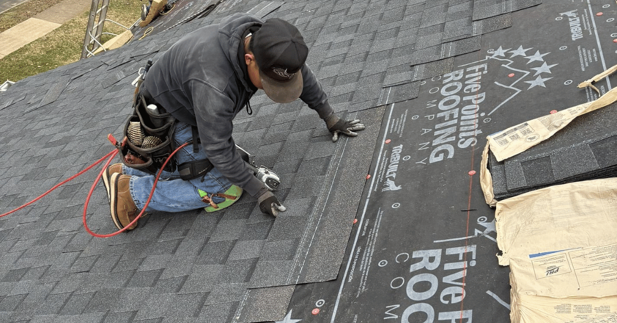 A professional roofer installing new asphalt shingles on a roof.