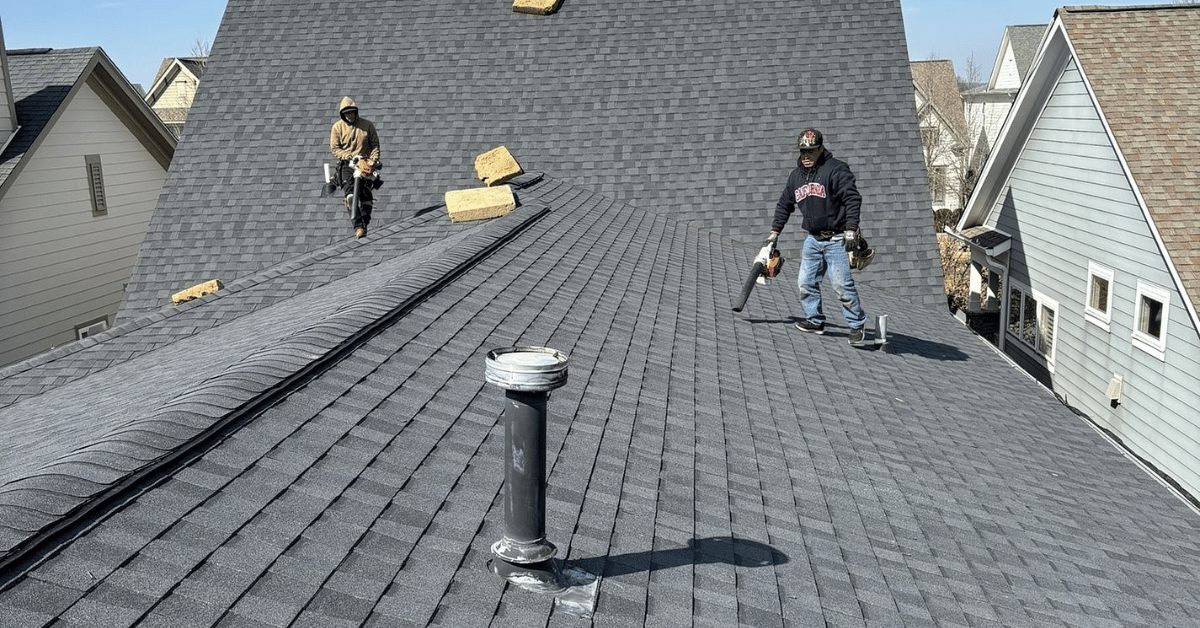 Two roofers conducting maintenance on a large residential roof