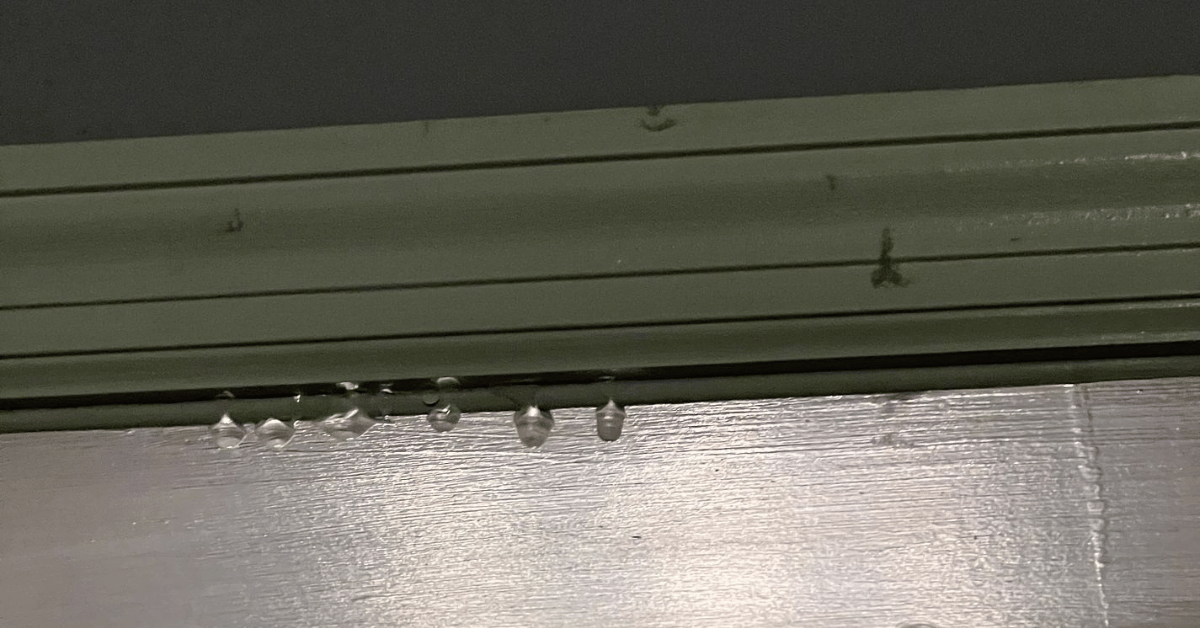 Close-up of water droplets forming under a trim, indicating a potential roof leak.