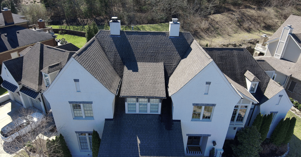 A drone-captured image of a large residential home with premature wear and tear TAMKO Heritage shingles installed.