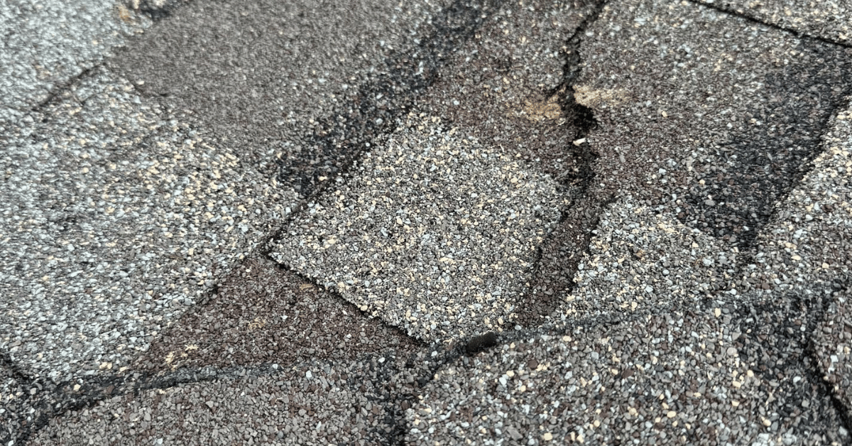 Cracked and worn asphalt shingles indicating roof damage