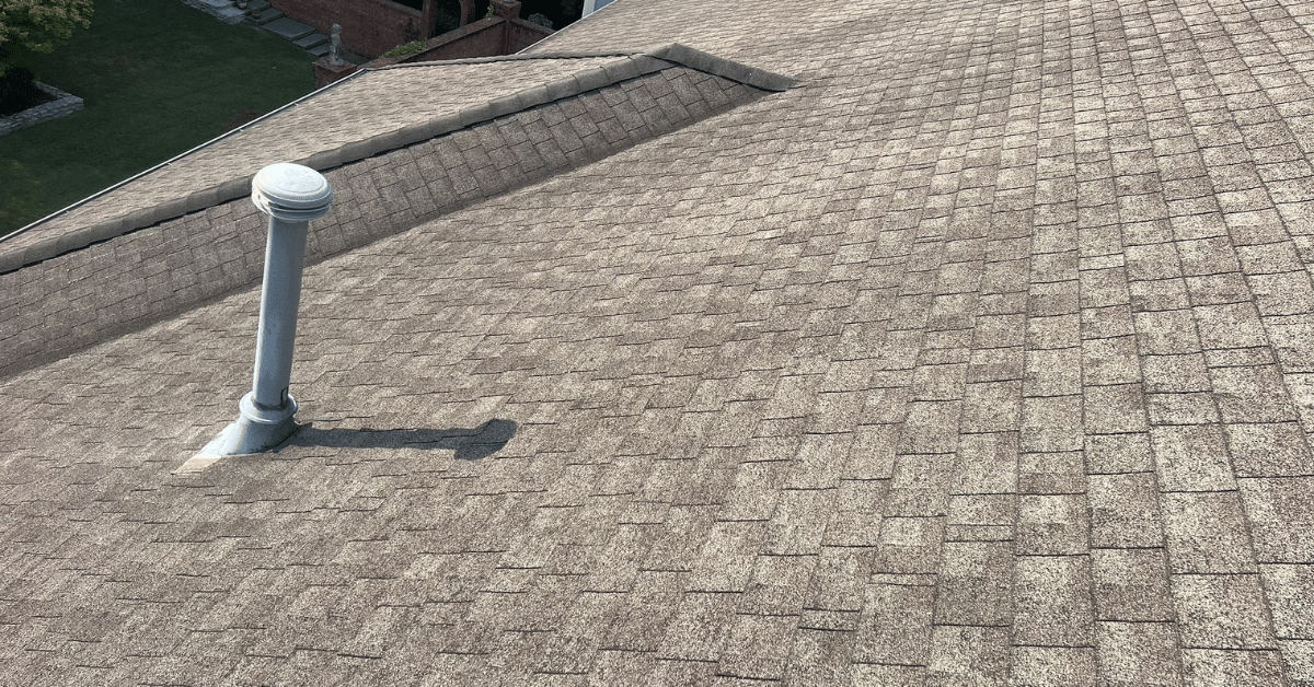 A close-up view of a newly installed asphalt shingle roof with a vent pipe.