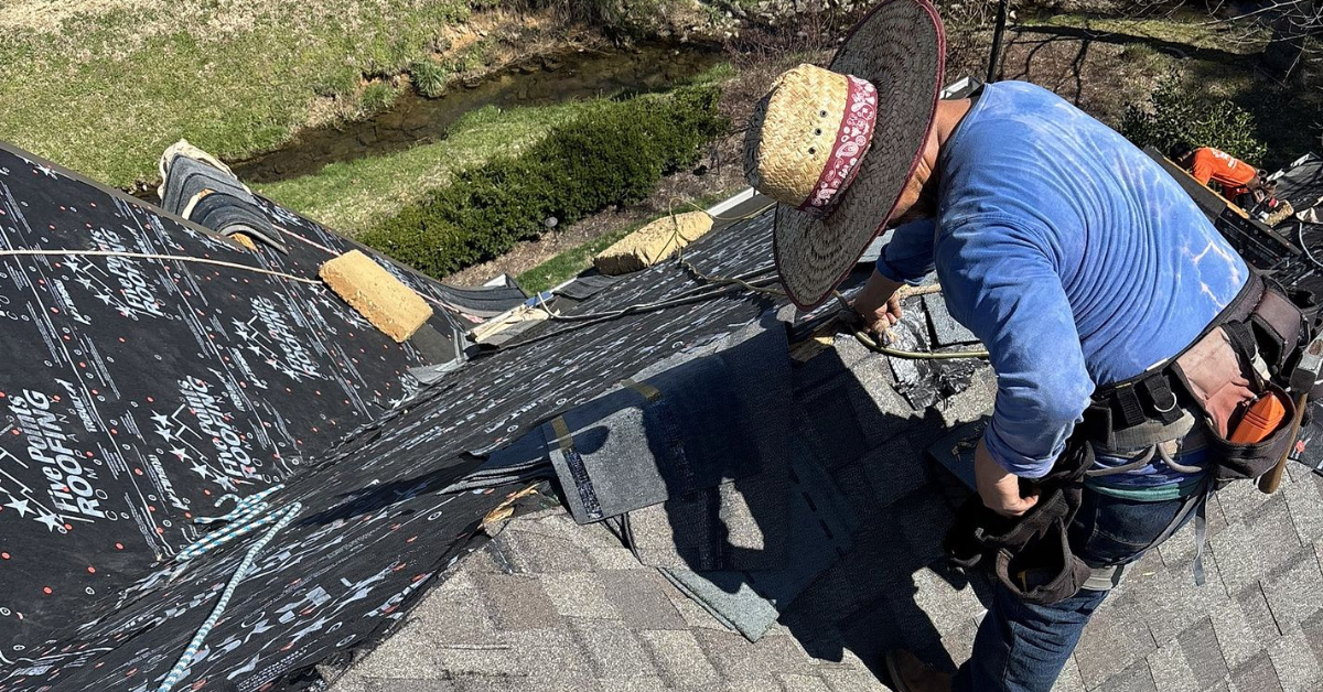 A roofing contractor securing shingles on a residential roof with Five Points Roofing branded underlayment visible.