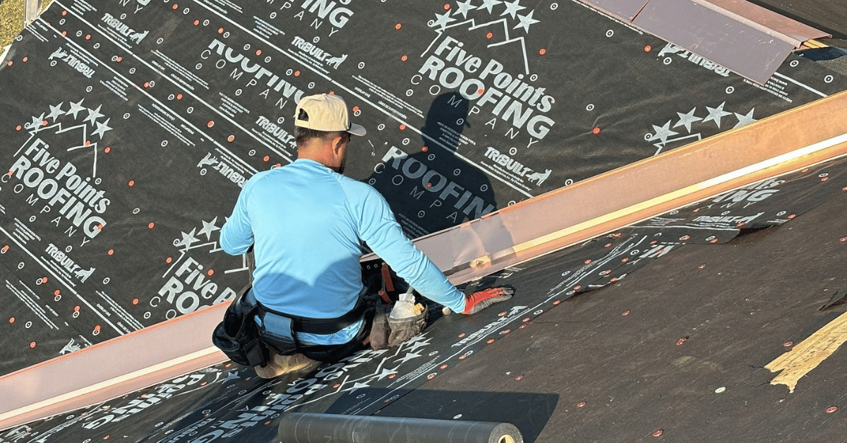 A Five Points Roofing professional roofer working on a roof installation, securing materials with precision.