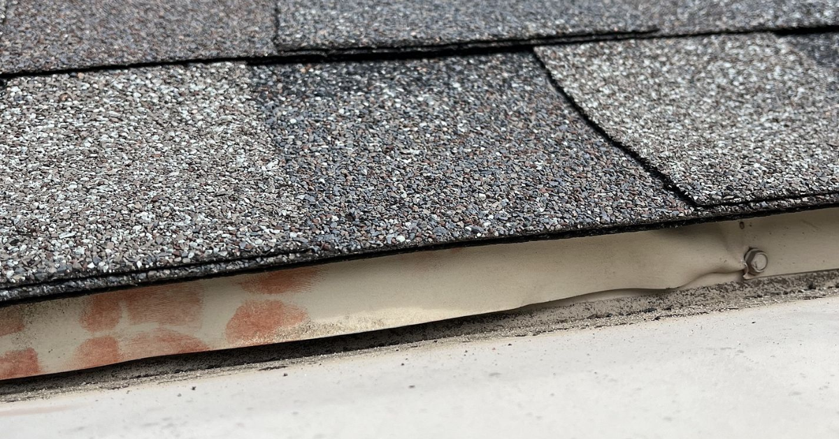 A close-up of improperly secured roof flashing with exposed edges.