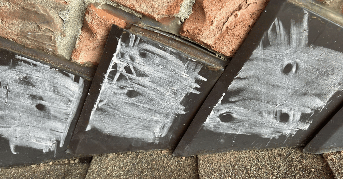 Roof flashing with chalk markings highlighting hail impact damage.