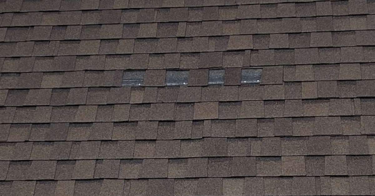 A roof with a few missing shingles exposing the adhesive backing.