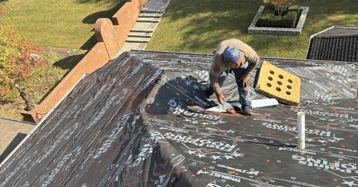A Five Points Roofing roofer installing protective underlayment branded with Five Points Roofing's logo
