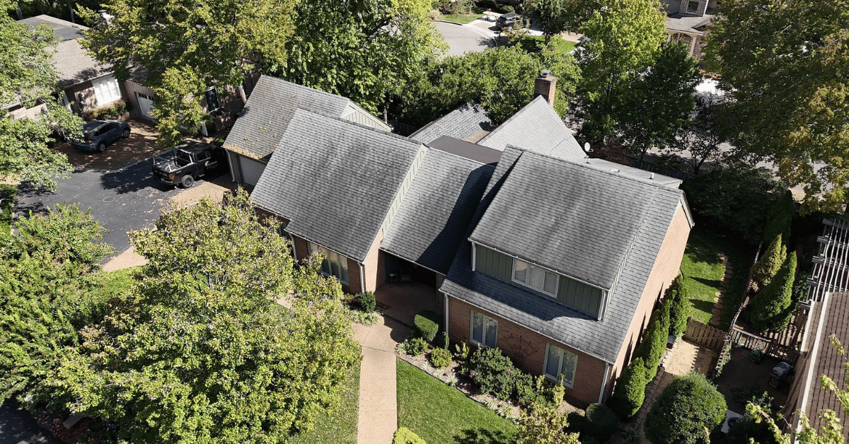 A residential home with asphalt shingles showing discoloration and signs of aging.