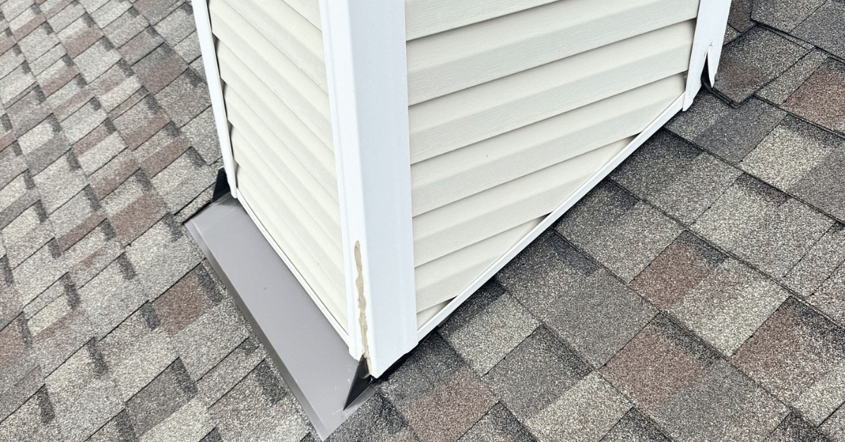 Close-up view of a chimney with new flashing installation on an architectural shingles roof, inspected for roofing contractor workmanship warranty coverage.