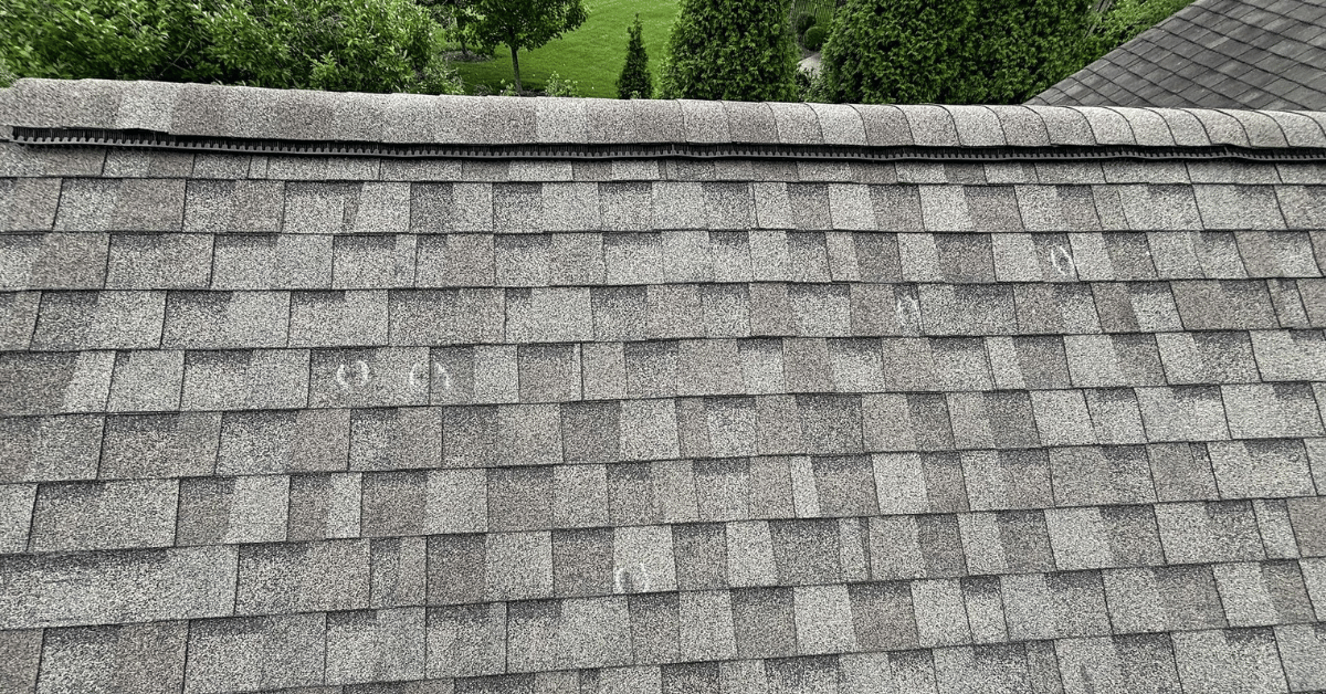 Marked shingle damage indicating hail impact during a professional roof inspection, used to evaluate insurance claim and replacement needs.