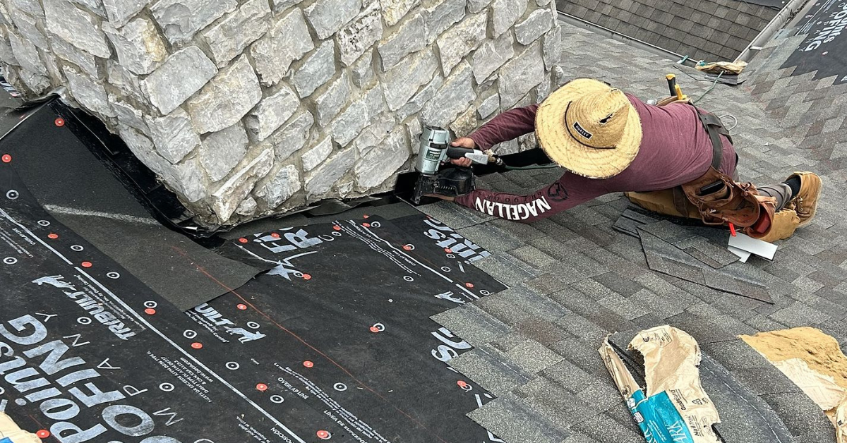 Close-up of a Five Points Roofing expert using flashing techniques for water-tight seal around chimney base during shingle installation.